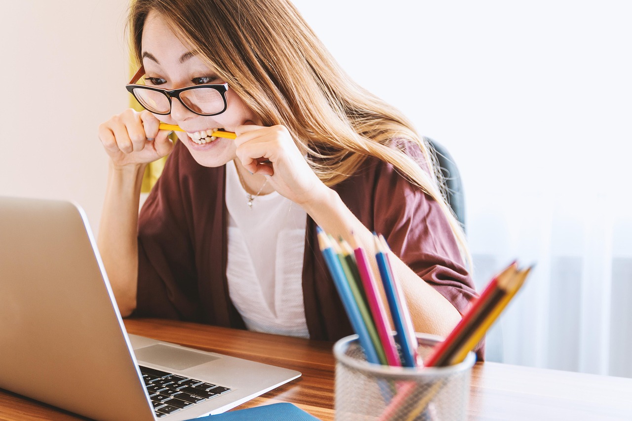 A person looking at a laptop screen thoughtfully while holding a credit card.