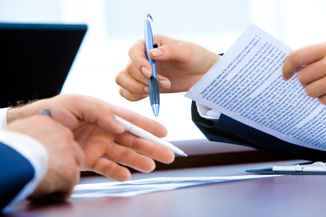 Two professionals shaking hands over documents in a bright office