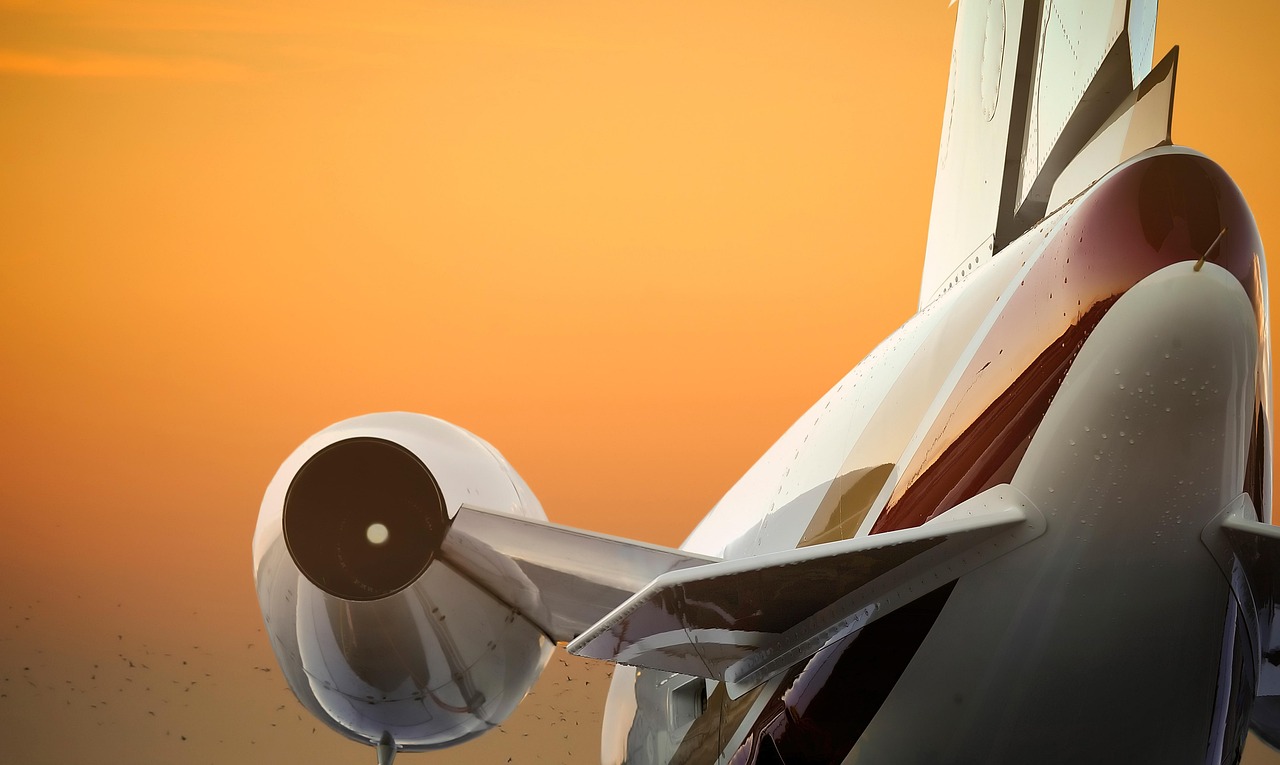 The wing of a private jet flying through clouds at sunset, symbolizing alternative investment access.