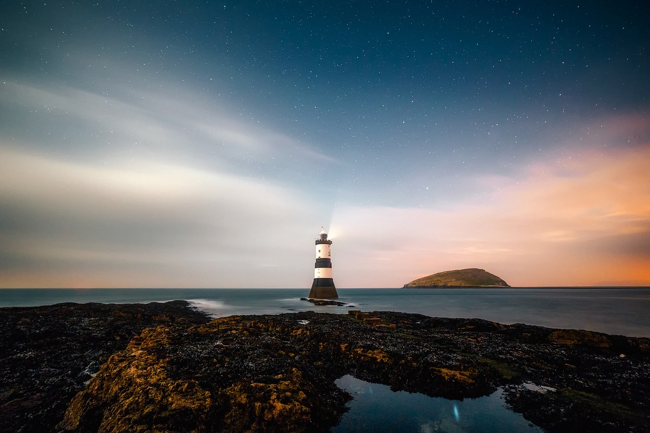 A bright lighthouse beam cutting through the dark night over a calm sea.