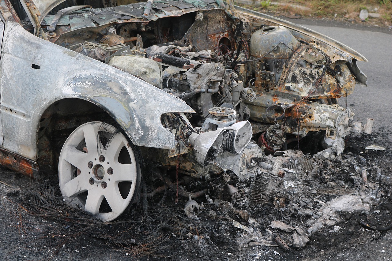 A person using a smartphone to take photos of a damaged car bumper at the scene