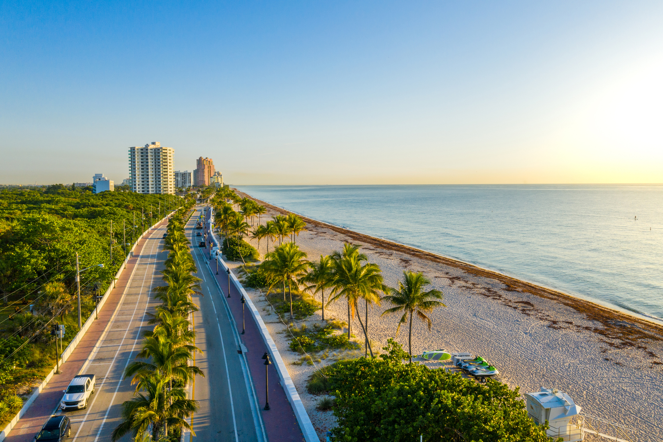 Aerial drone view of a beach road lined with palm trees in Miami, Florida.