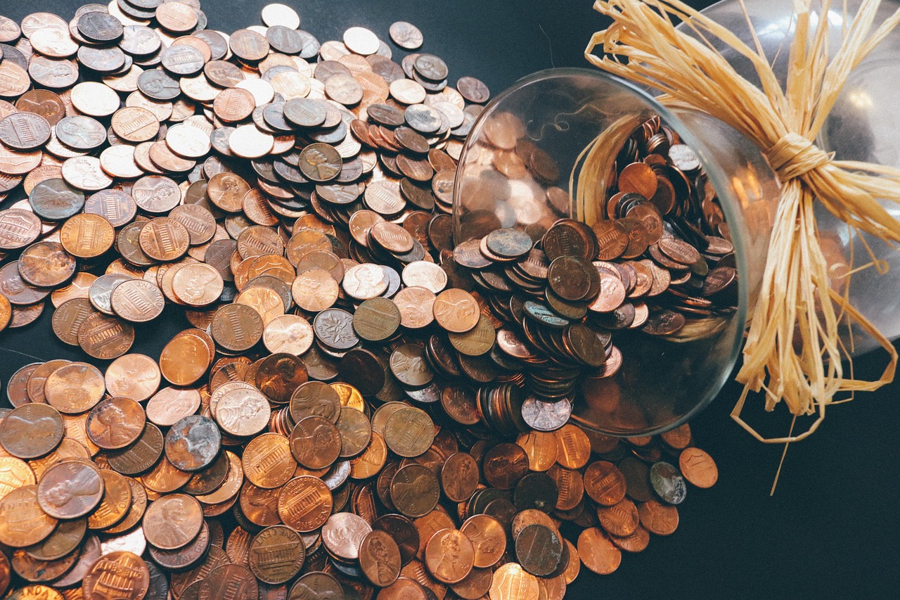 A small green plant growing out of a jar full of coins, representing steady financial growth.