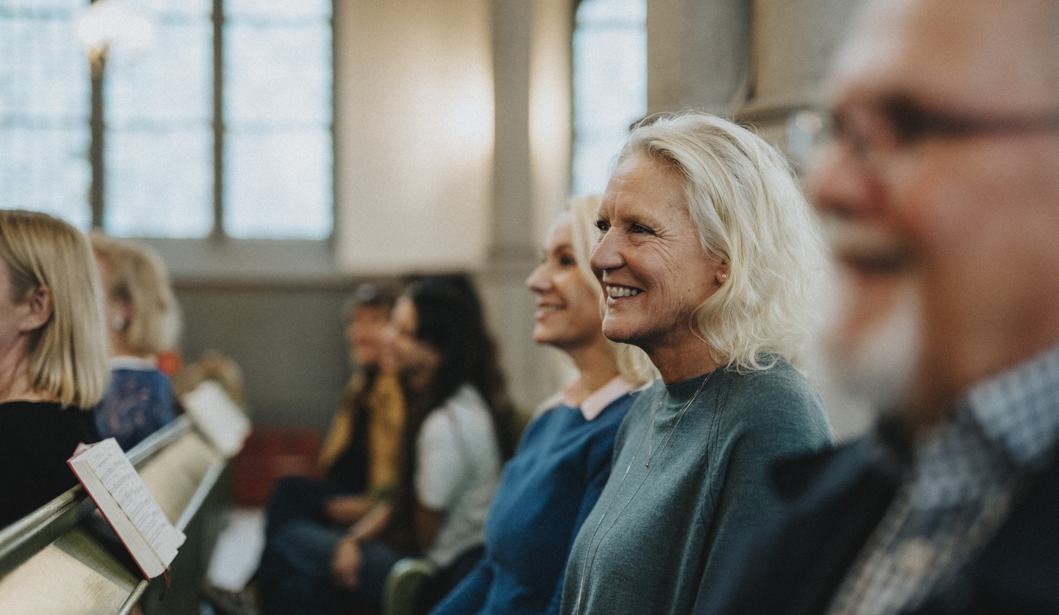 A smiling elderly couple and their adult daughter attending a church service together.