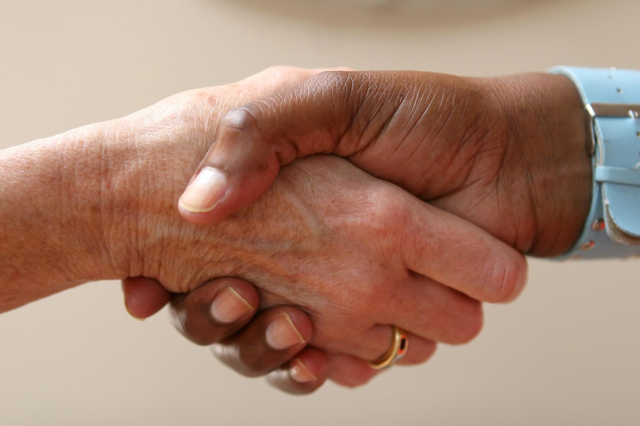 Two people shaking hands in a bright, modern office setting, representing a successful financial start.