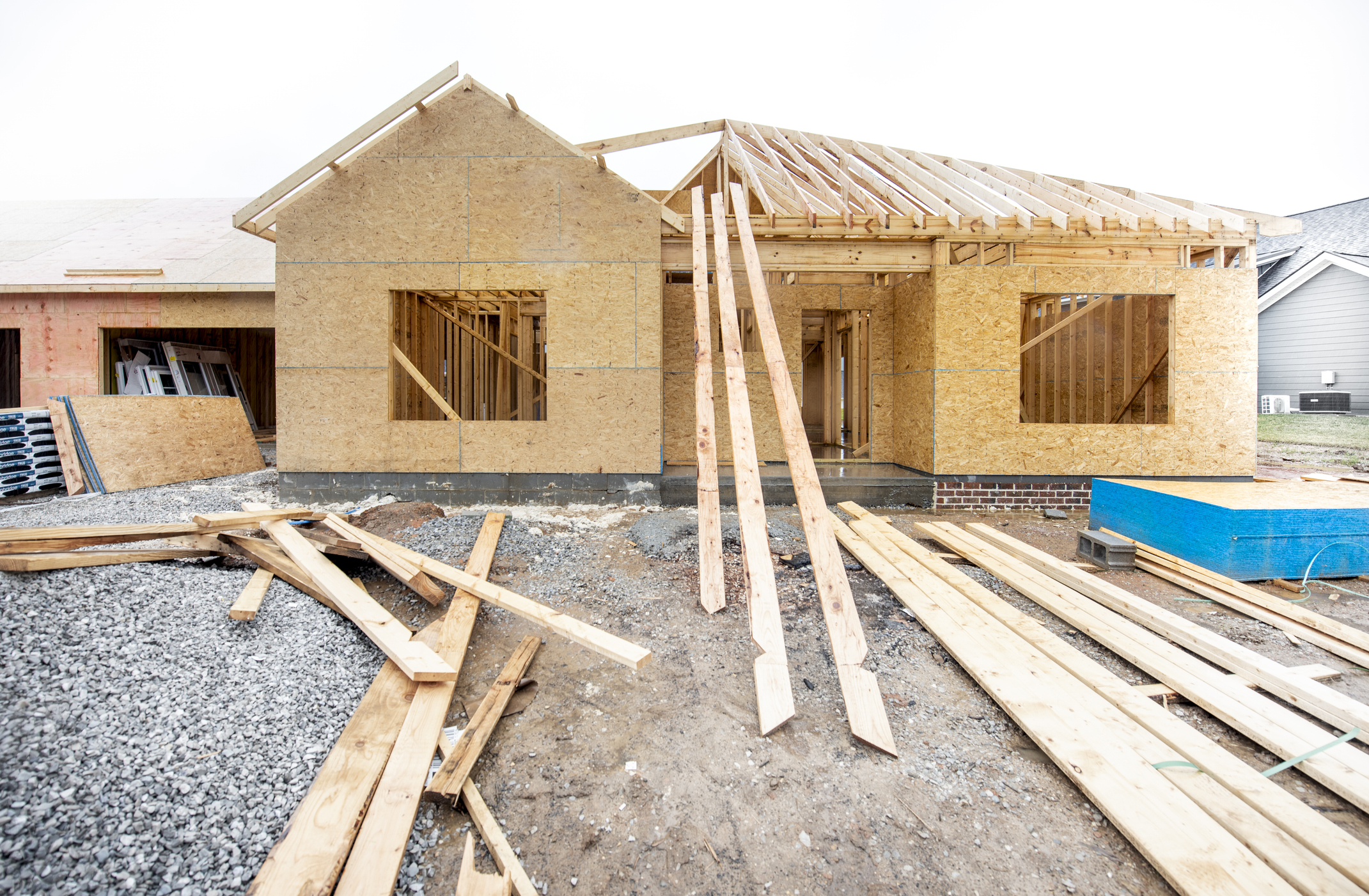 A new residential structure under construction with wooden framing and industrial equipment present.