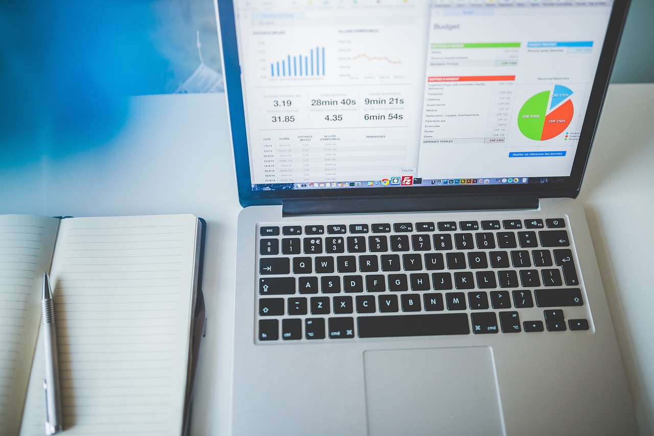 A professional using a financial calculator and laptop to verify account balances and insurance limits.