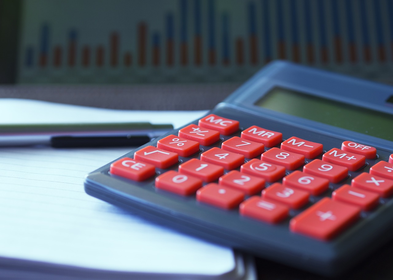 A calculator and US dollar bills on a clean office desk.
