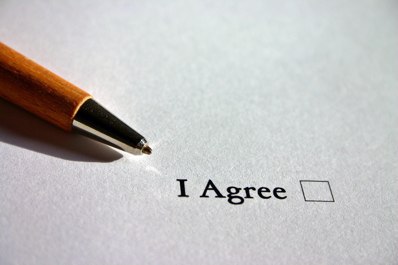 A person reviewing an insurance policy document and holding a pen over a claim form.