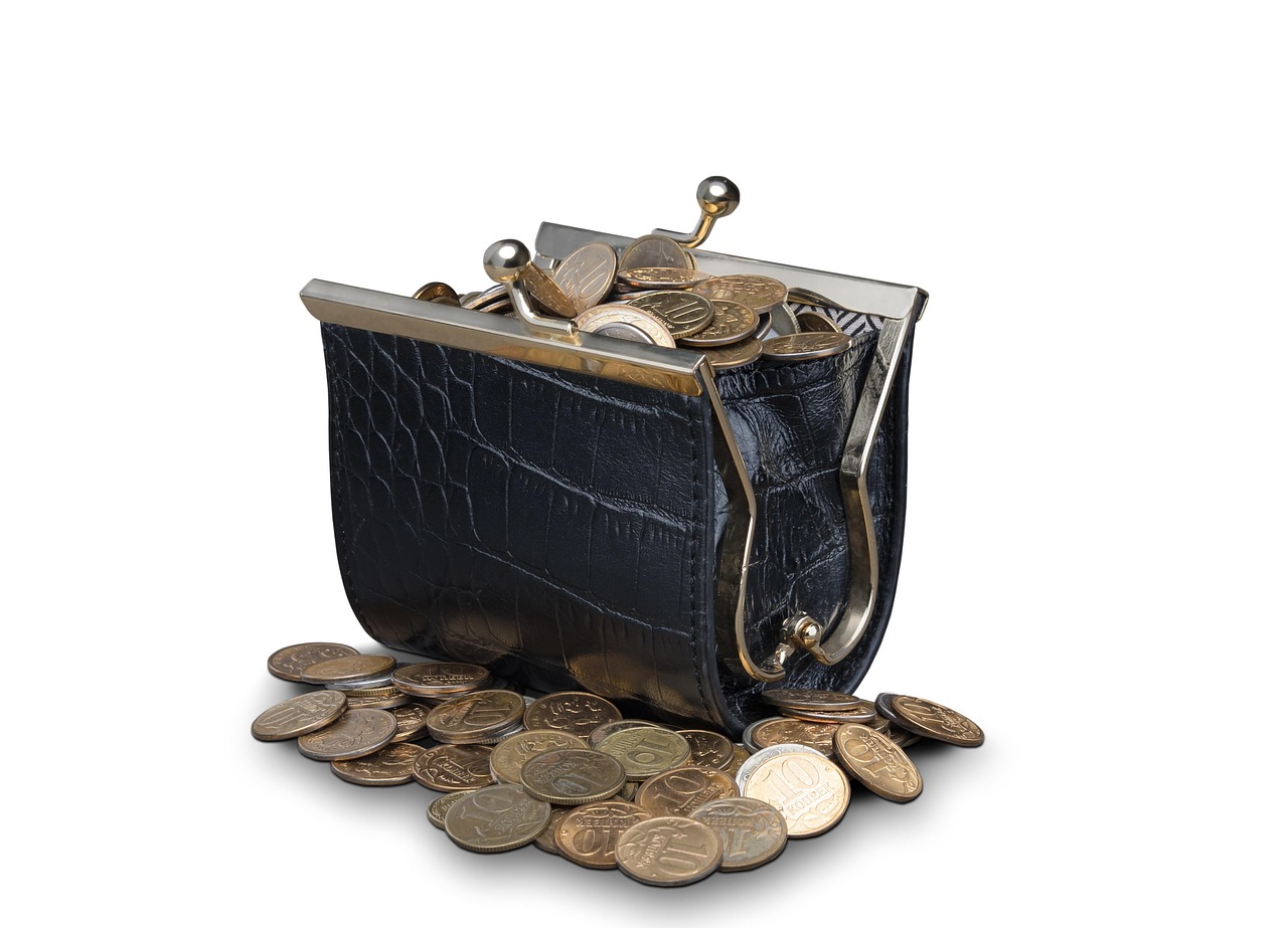 A hand placing coins into a leather purse on a wooden table, symbolizing fee deductions.