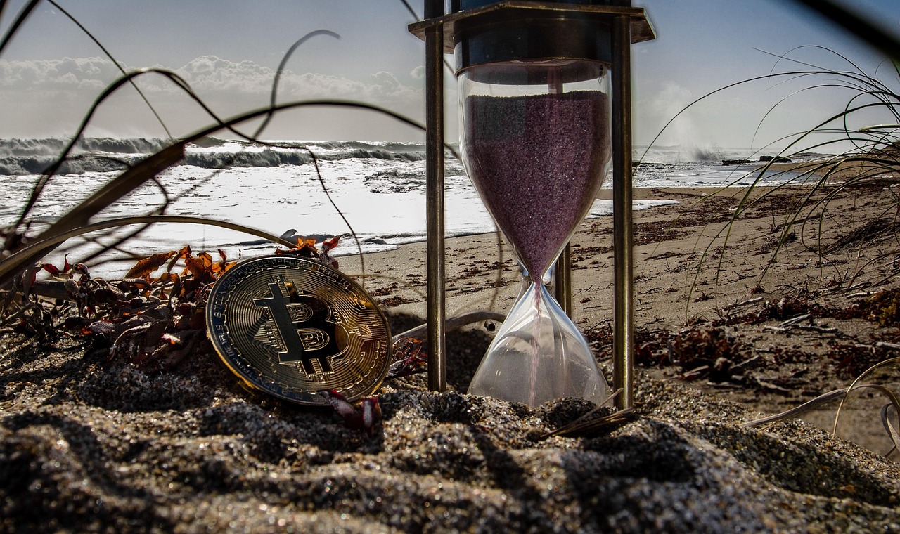 An hourglass with gold coins at the bottom representing the passage of time and investment value.