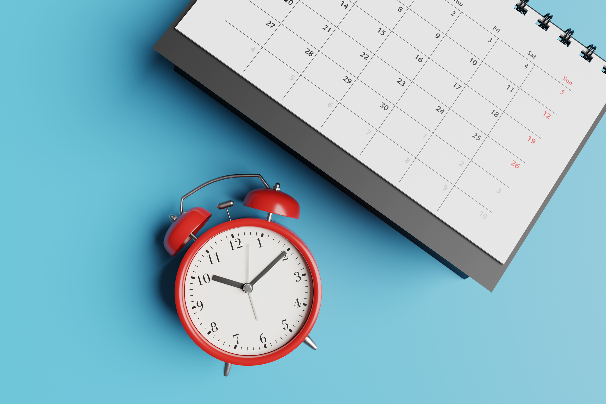 A red analog clock sitting next to a calendar on a bright blue background, symbolizing deadlines and scheduling.