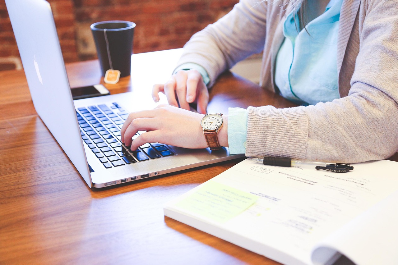Hands drafting a formal letter on a professional desk.