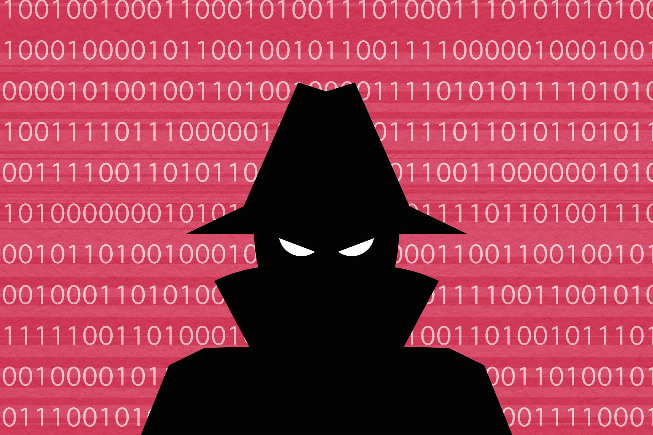 A dark silhouette of a person at a computer representing cyber security risks.