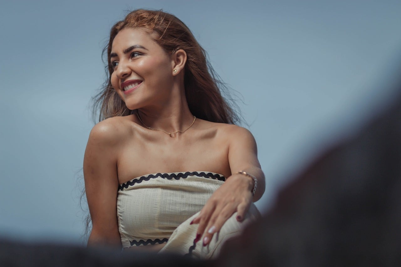 A person smiling confidently with perfect teeth in a bright outdoor setting.
