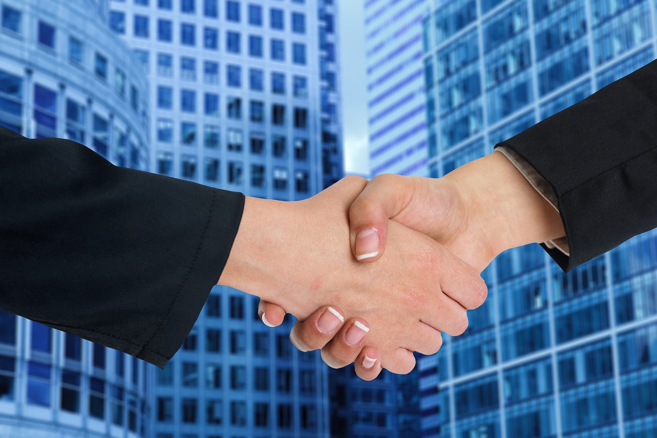 A zoomed-in professional handshake in an office setting, representing a successful financial decision.