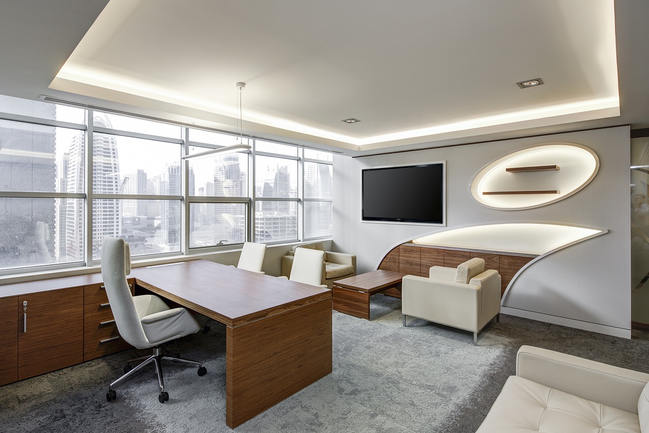 A busy office desk with multiple monitors and structured document piles.