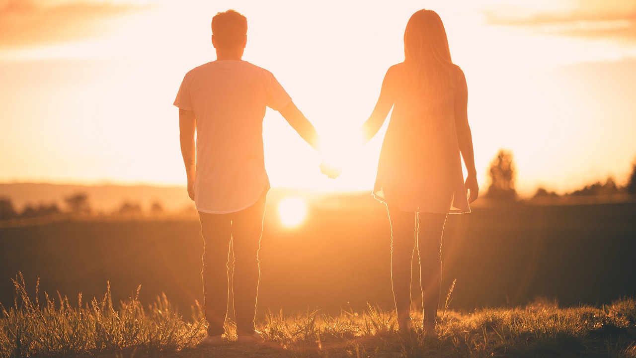 A man handing his car keys over to a female friend in a suburban driveway.