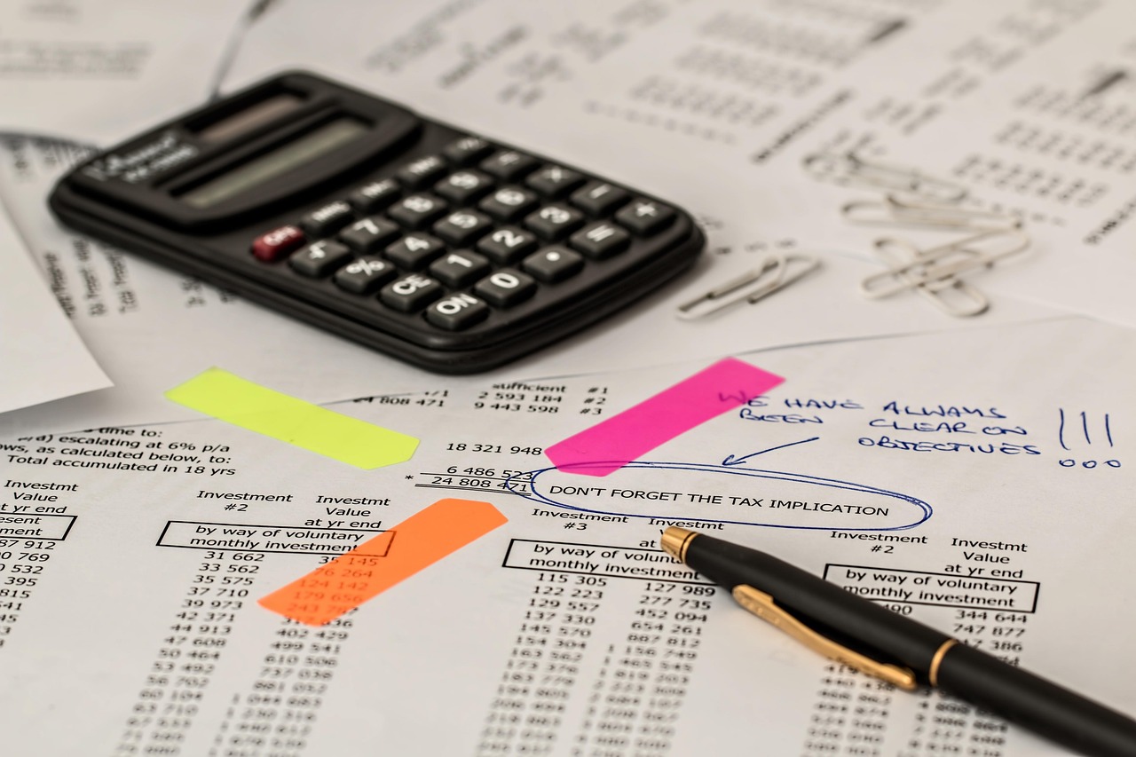 High-angle view of a desk with a calculator and tax forms representing fiscal compliance.