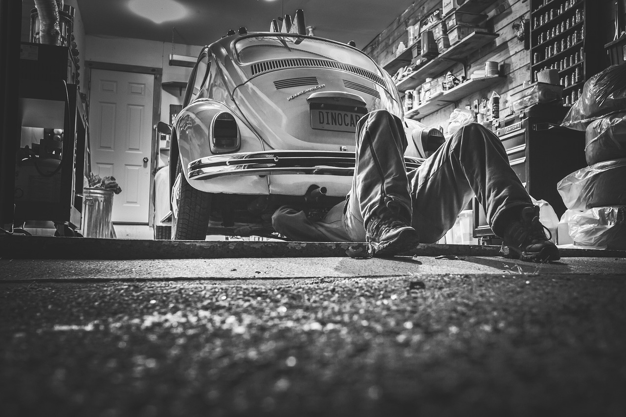 A professional mechanic inspecting the undercarriage of a car in an auto shop.