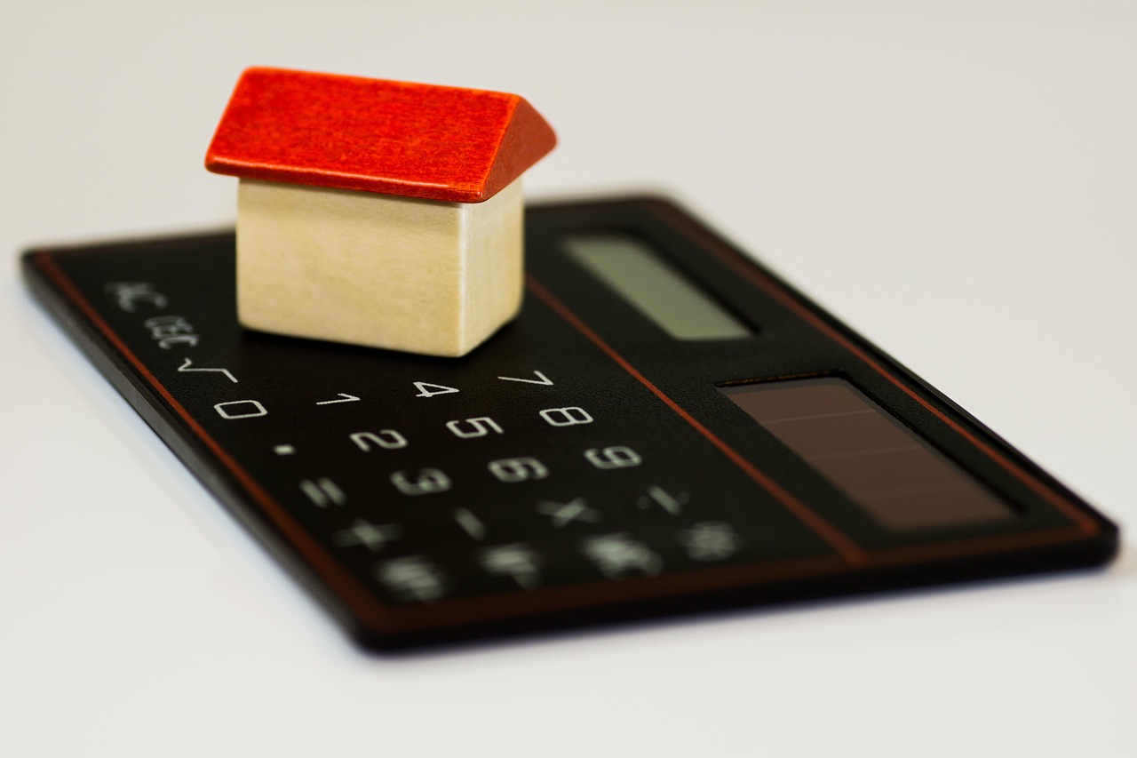 A calculator, dental mirror, and coins on a white desk representing dental financial planning.