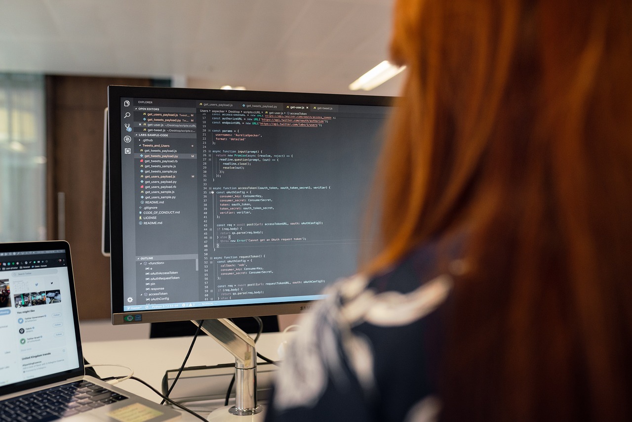 A developer working on a laptop at a clean workstation with lines of code visible on the screen.