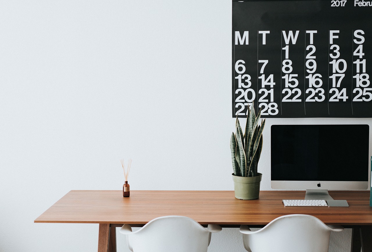 A luxury wristwatch and a calendar on a clean office desk.