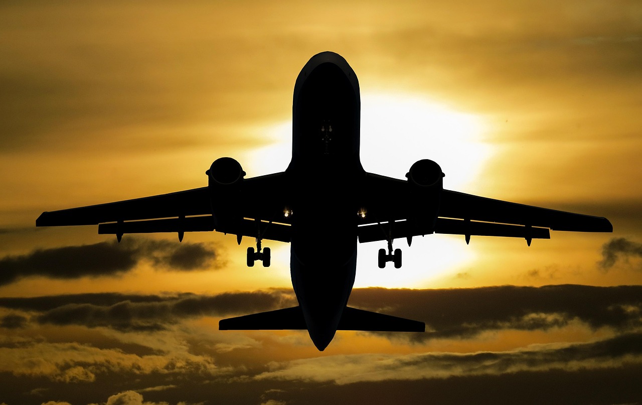A large commercial aircraft flying through a colorful sunset sky.