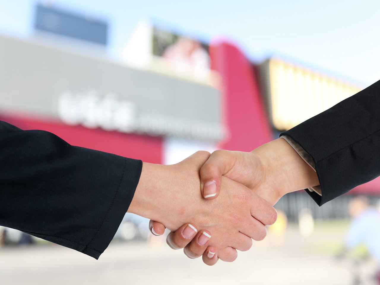 Two business professionals shaking hands in an office, representing a successful negotiation or agreement.