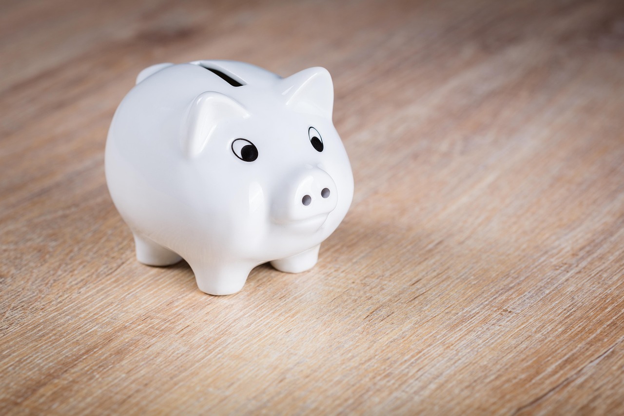 A white piggy bank with a house key symbolizing long-term savings security.