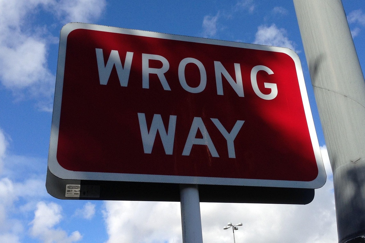 A wooden signpost with multiple arrows pointing to different directions under a clear sky.
