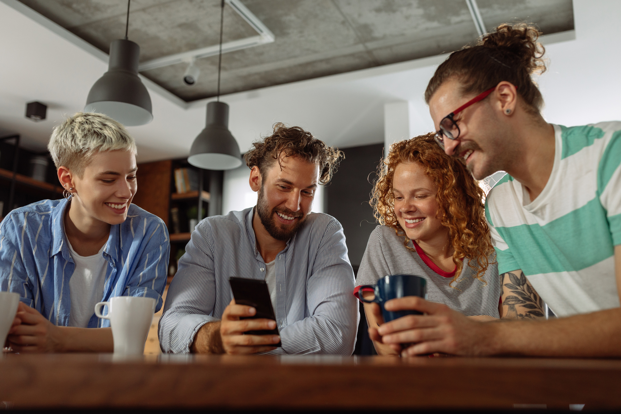 A group of diverse friends sitting together on a couch using their smartphones in a cozy living room.