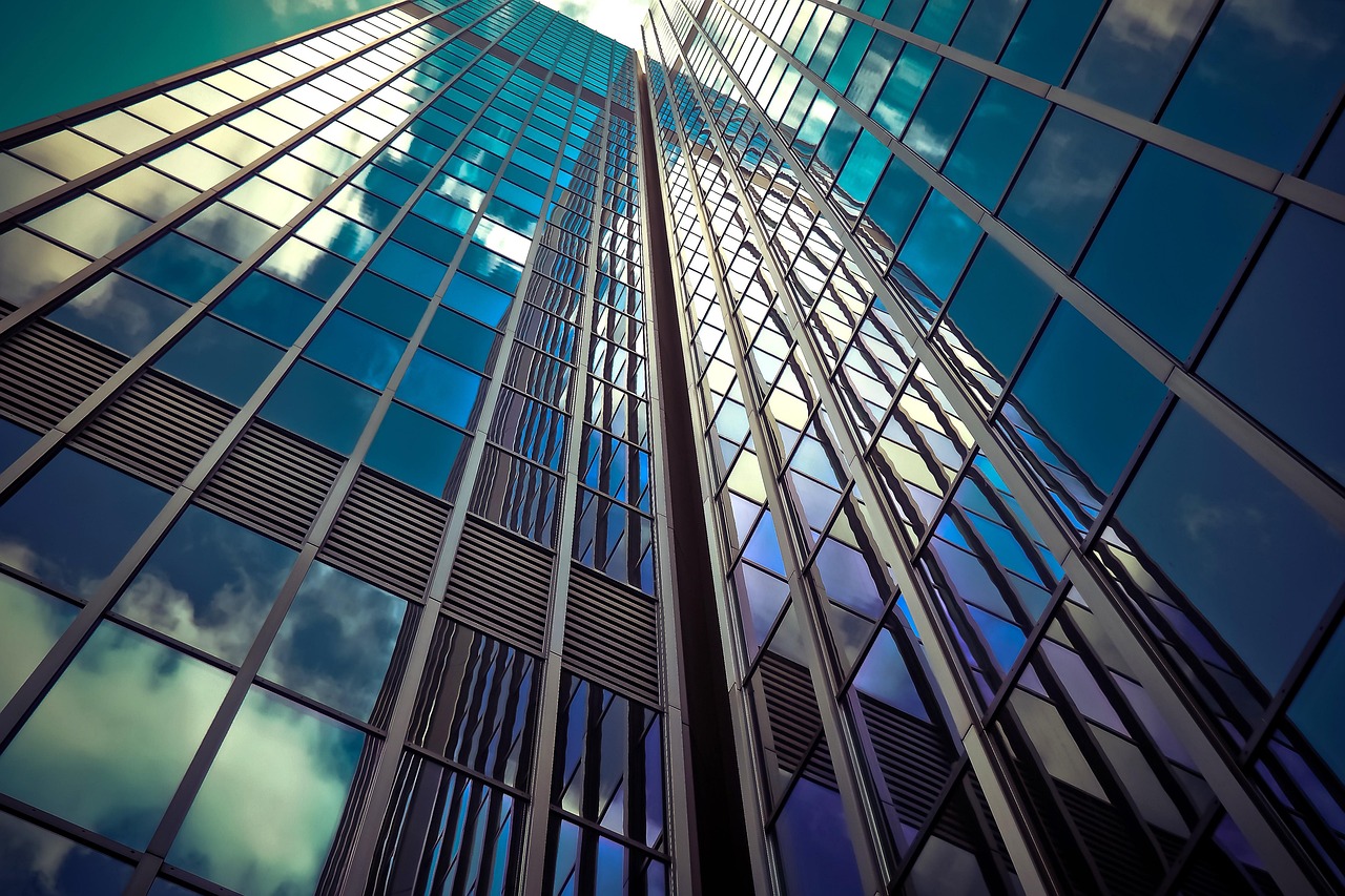 A wide shot of a modern glass skyscraper reflecting a clear sky, symbolizing institutional stability and clear financial foresight.