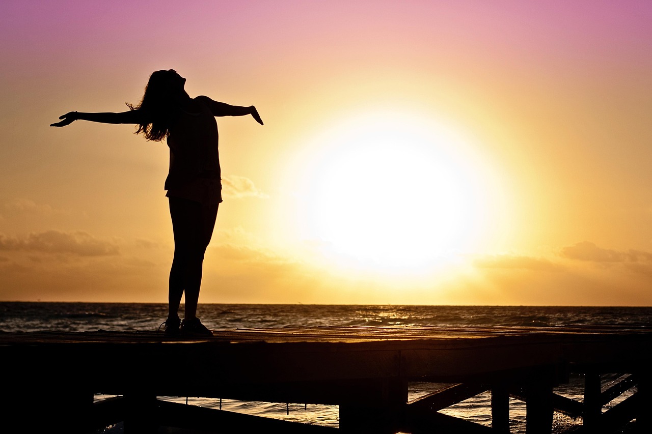 A person standing calmly by the ocean during sunrise representing financial freedom and peace