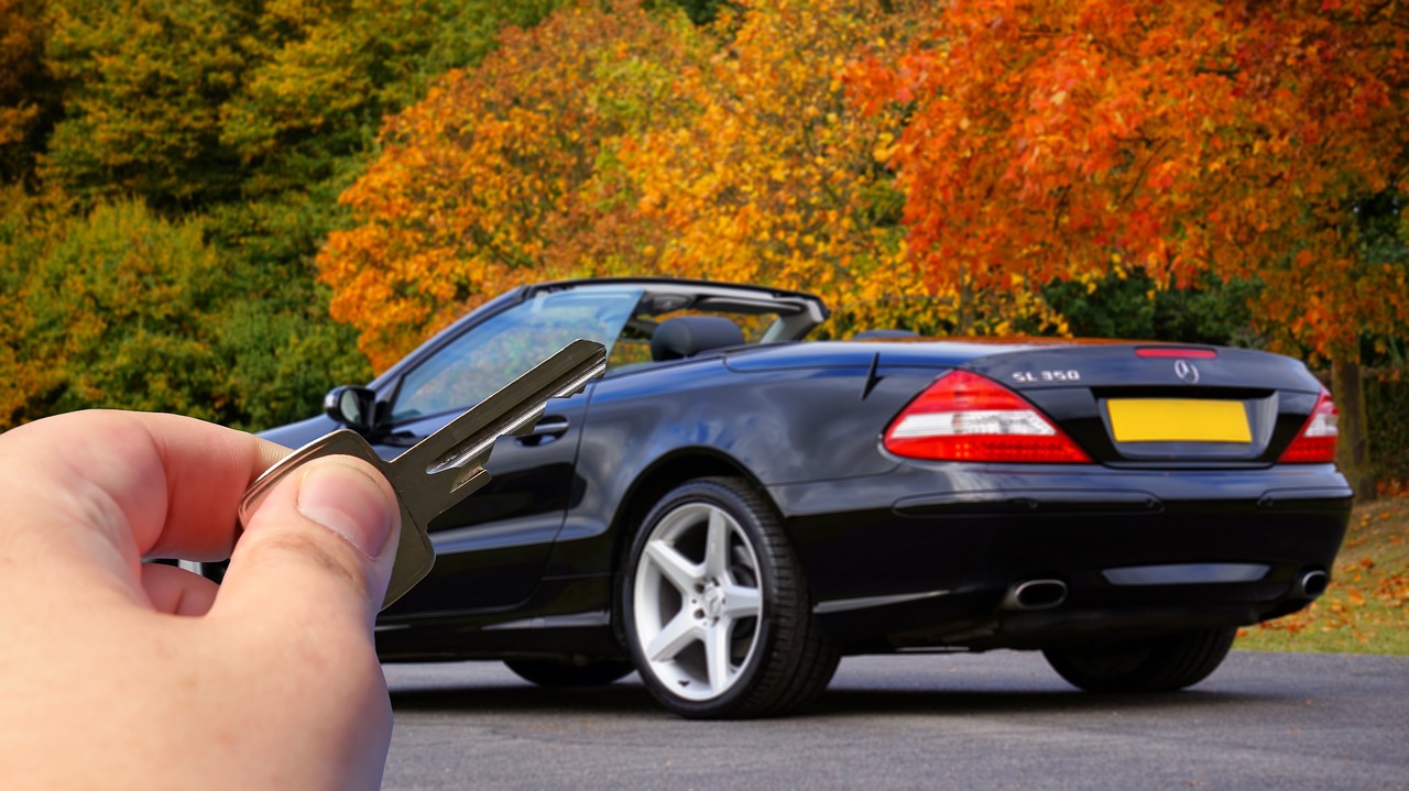A hand holding a car key with a keychain, representing the purchase of a first vehicle.
