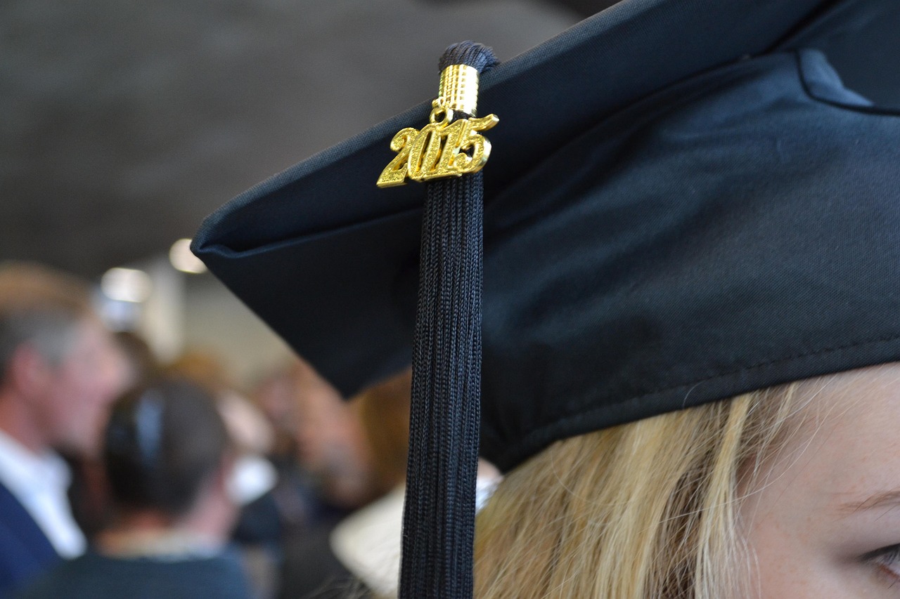 A graduation mortarboard placed next to car keys on a clean wooden desk
