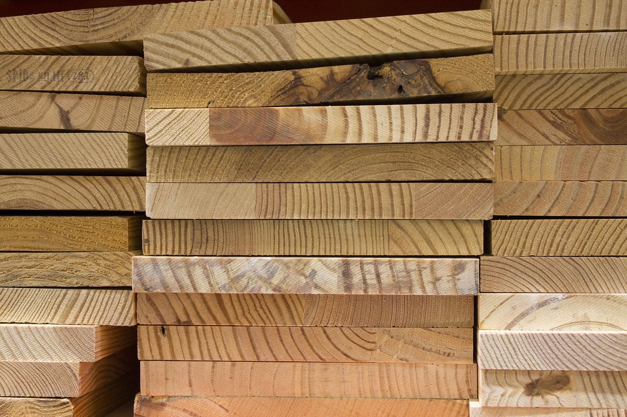 Large stacks of lumber at a construction site representing rising material costs.