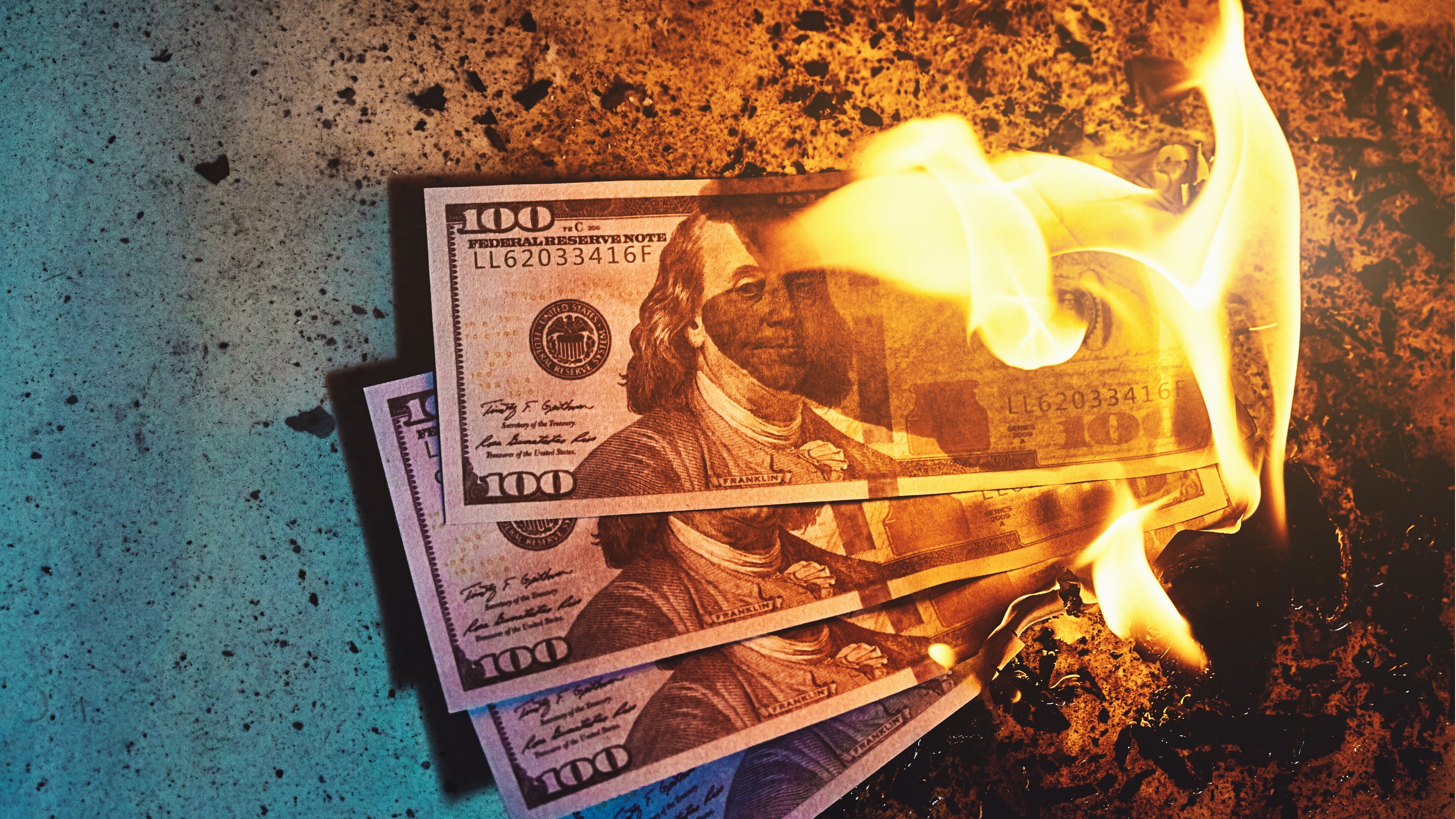 Multiple one-hundred-dollar bills caught in flames.