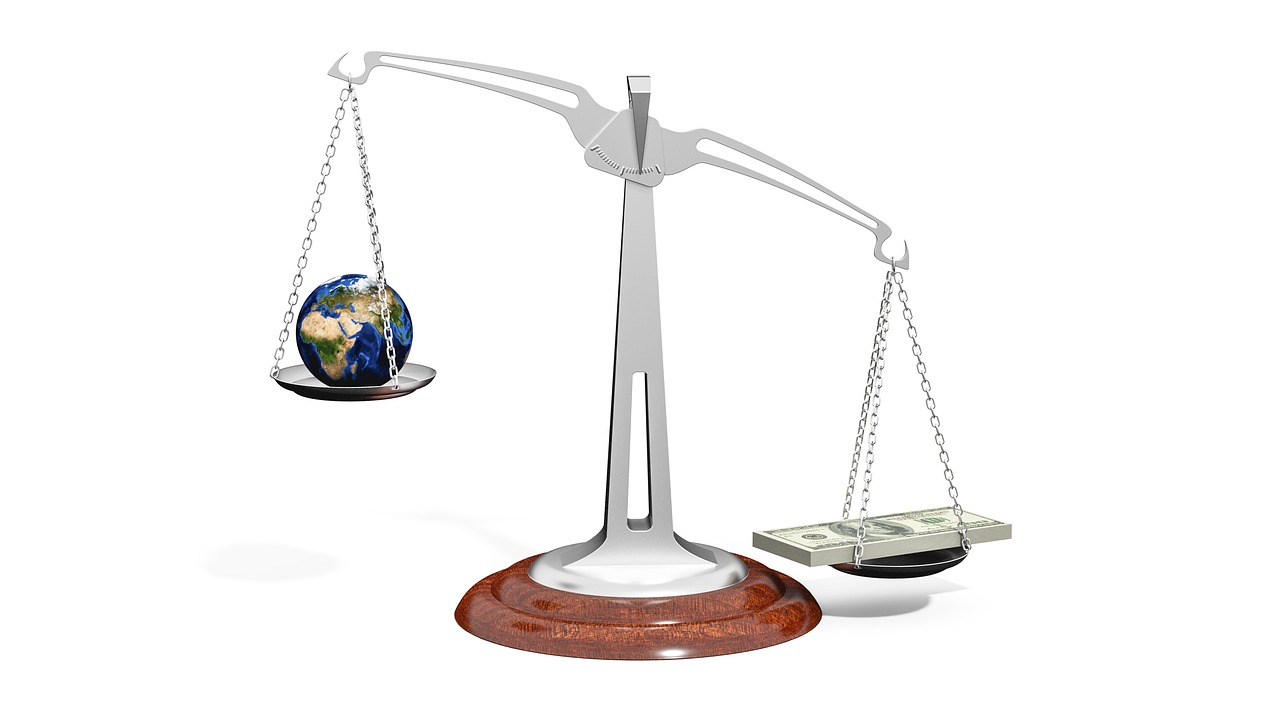 A magnifying glass placed over a world map with various international currency symbols.