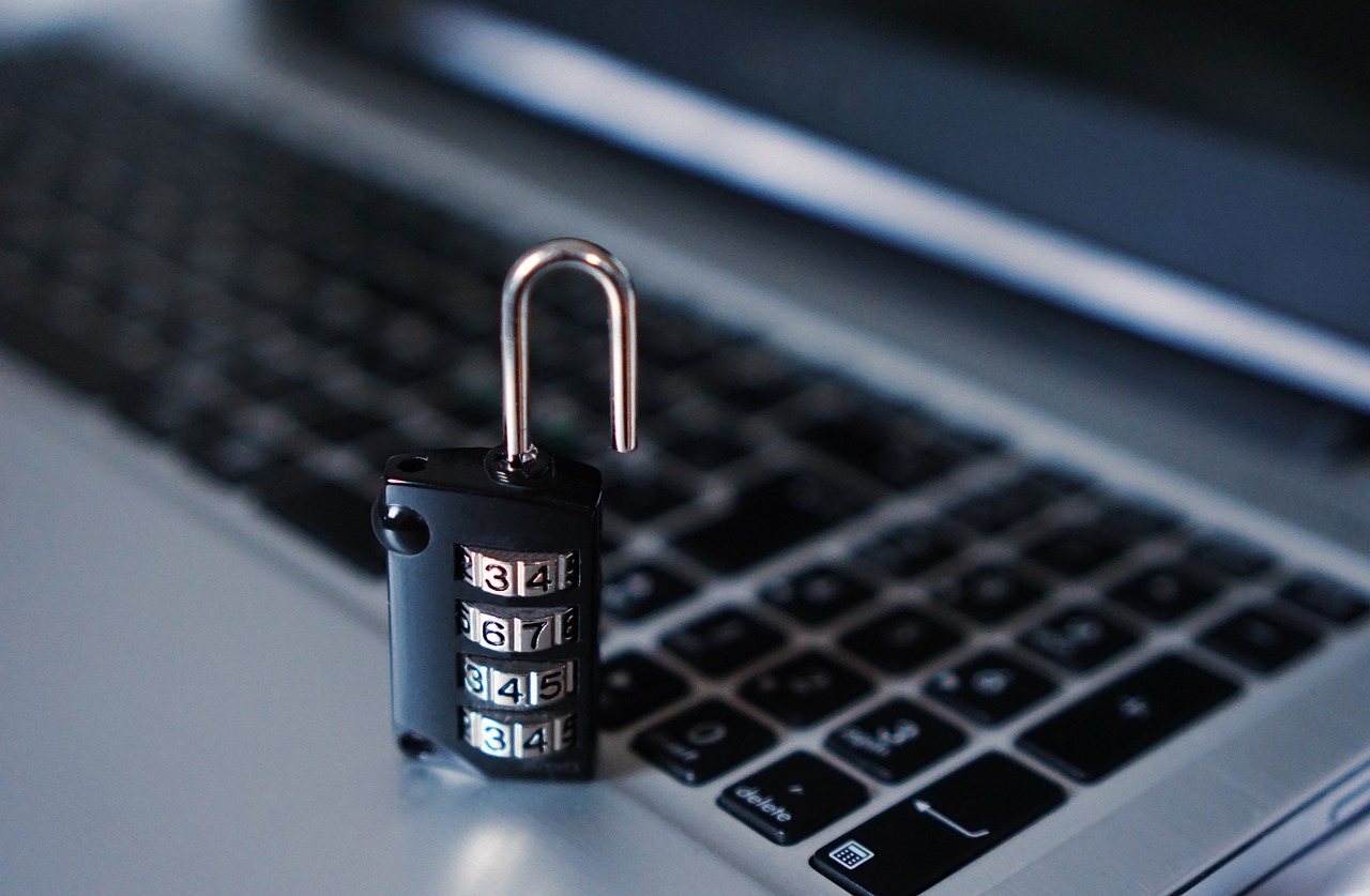 A physical padlock sitting on a digital laptop keyboard representing account security.