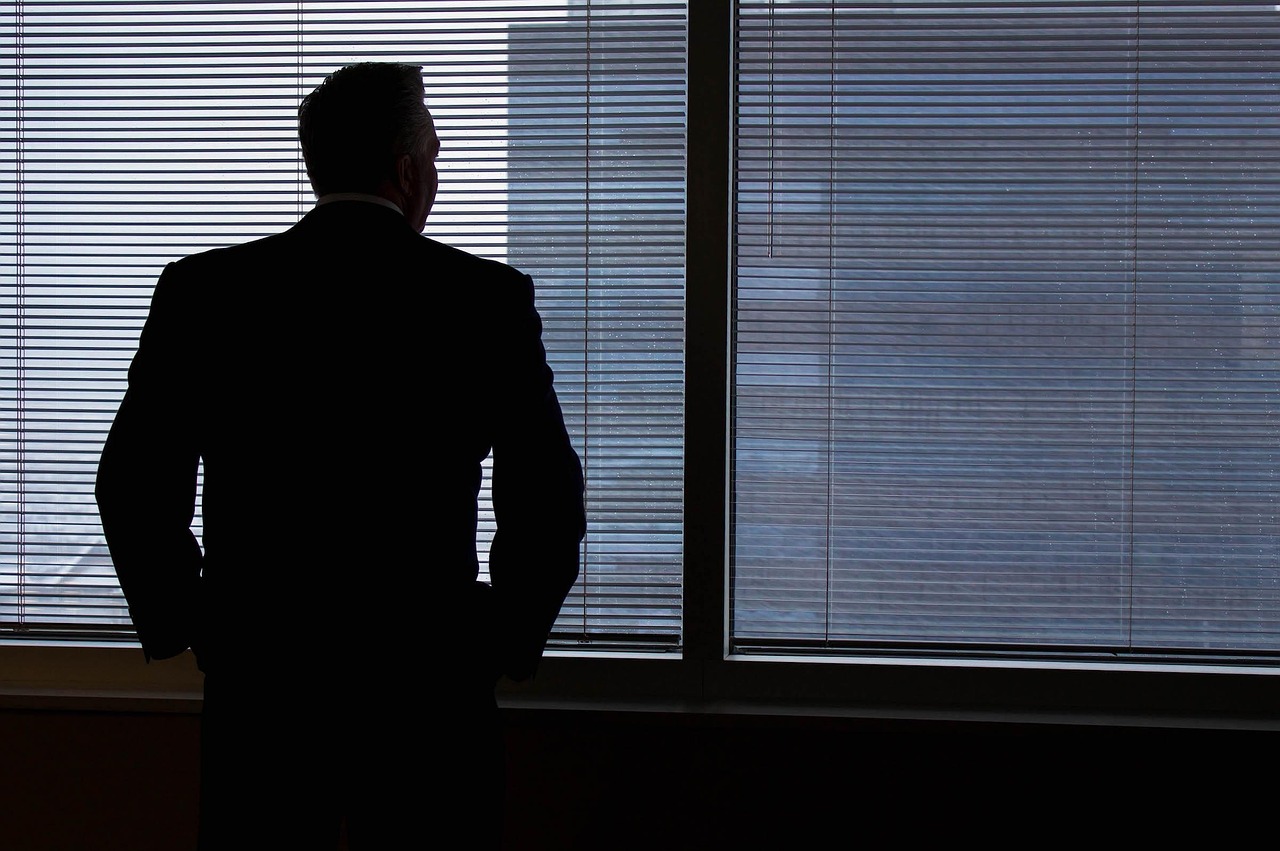 A high-rise office window overlooking a bustling city skyline during sunset.